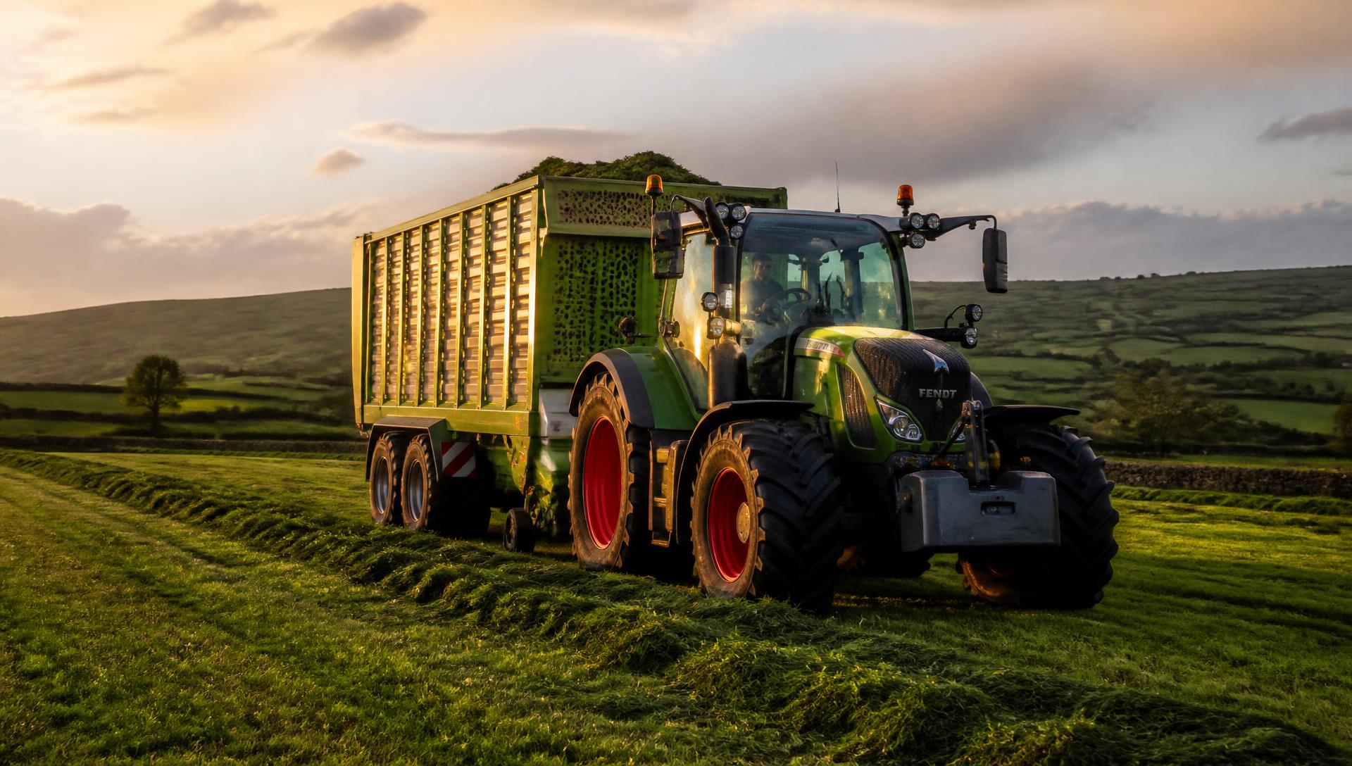 Tractor and silage trailer working in an Irish field at golden hour
